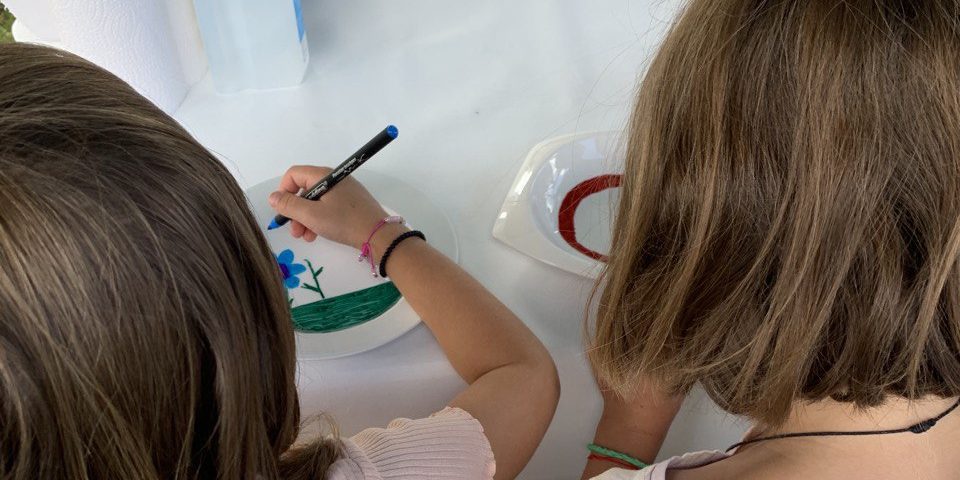 Kinder bemalen weißes Geschirr mit Stiften